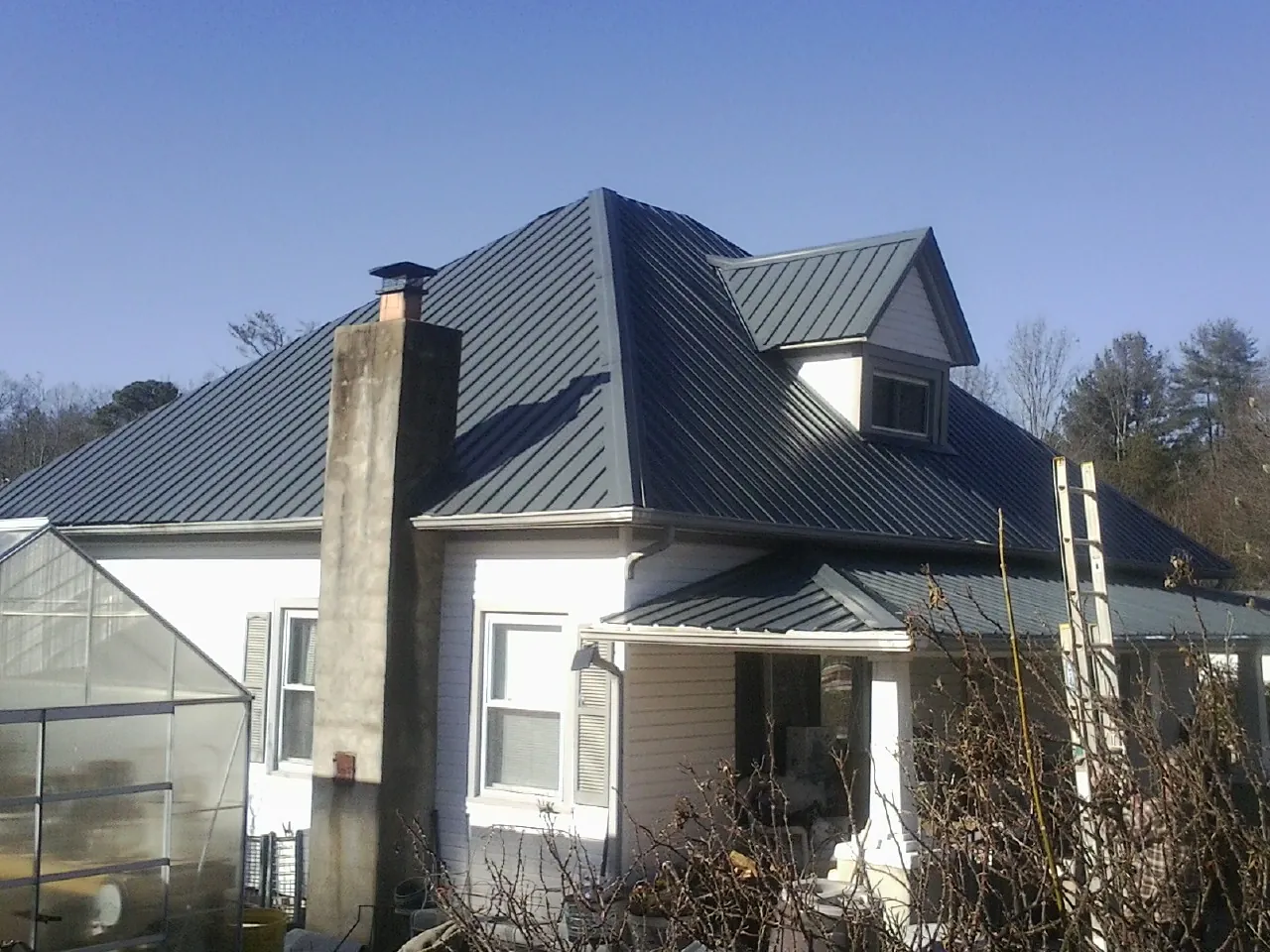 Dark blue standing seam metal roof on a white farmhouse with dormer — Slate & Tile Roof Repair by Roofing Brothers in Pottersville