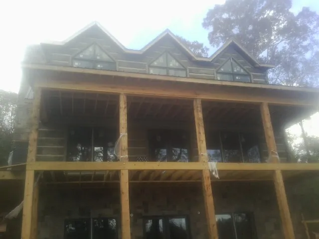 Dormers and porch framing on a large log home under construction — Roof Coating work by our crew in Pottersville