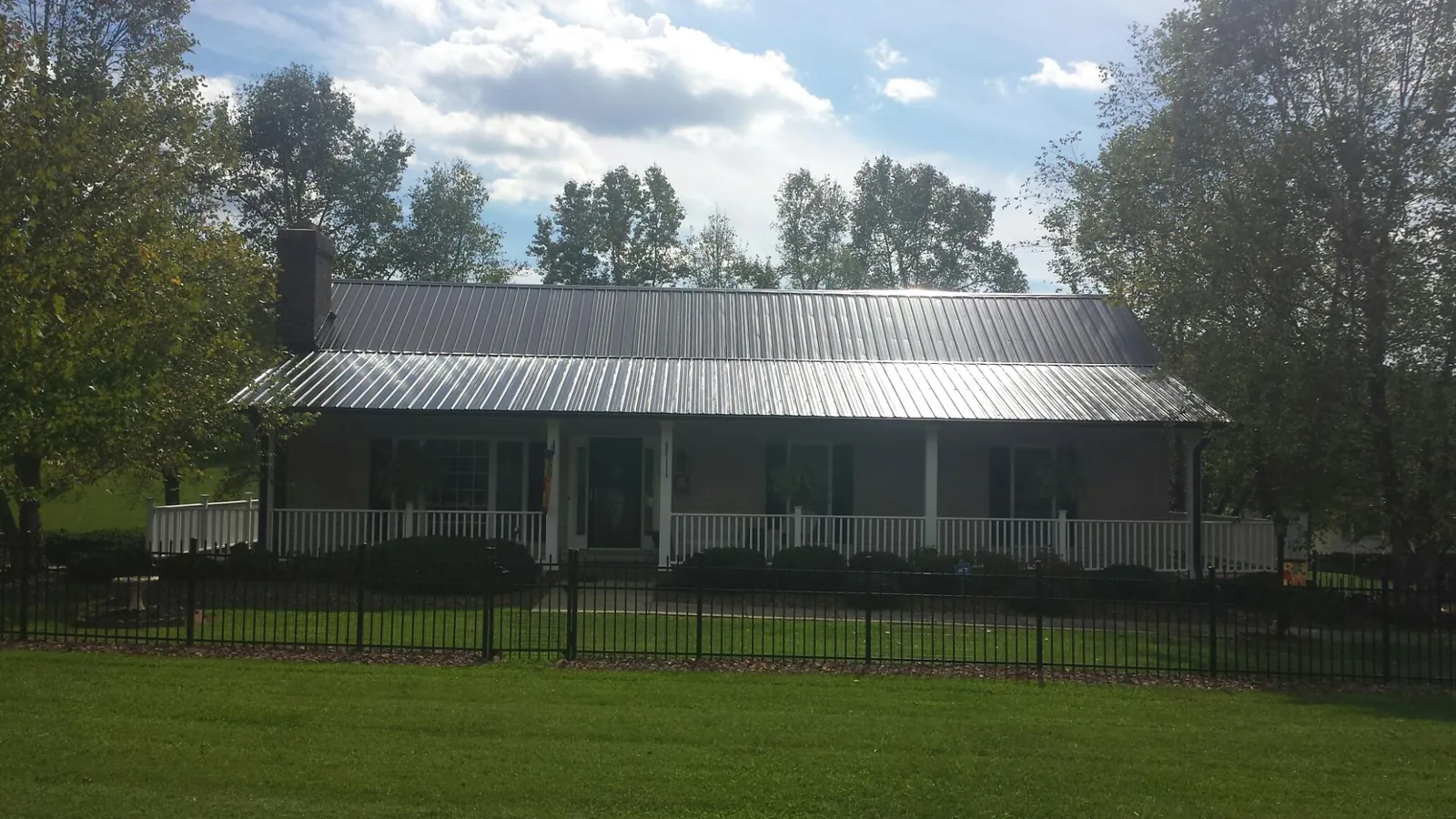 Gray metal roof on a brick ranch with a full width front porch — Gutter Guard Installation work by our crew in Pottersville