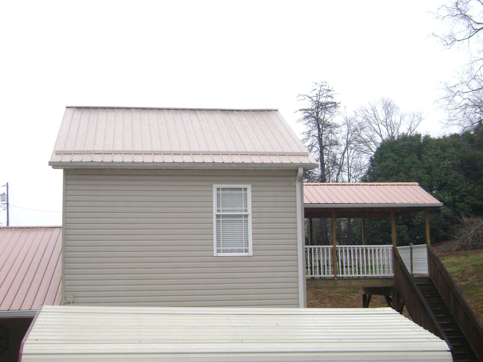 Tan metal roofs on a two story addition and attached porch, from a Roof Replacement job in Pottersville