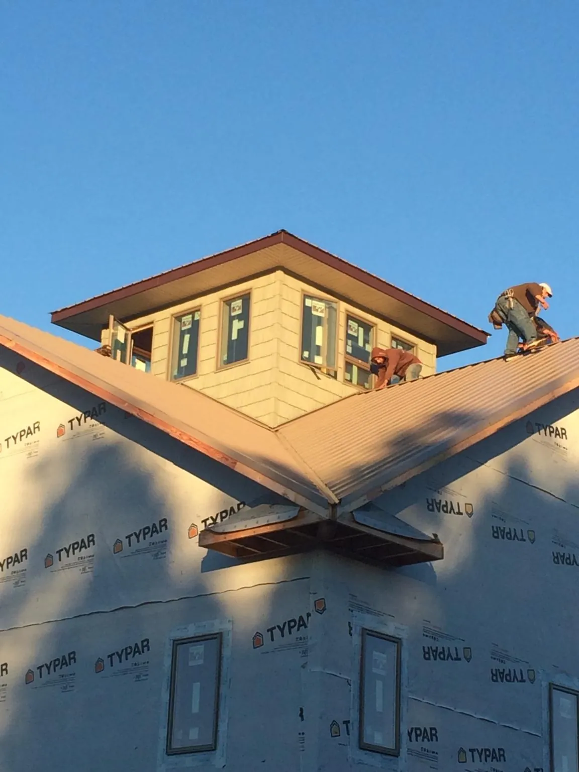 Roofers working around a rooftop cupola on a new metal roof at sunset — Roof Waterproofing in Pottersville by Roofing Brothers